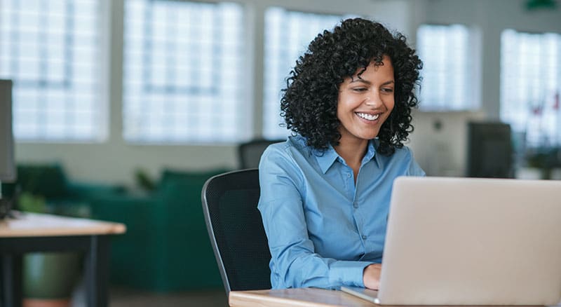 Everlytic | Blog | 4 Tips to Consider When Reviewing Your Email Sending Frequency | Young Professional Lady Smiling While Working in Office