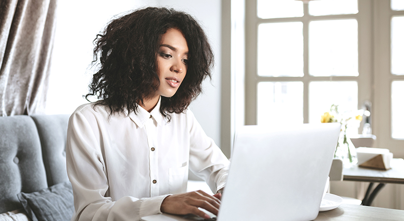 Everlytic | Blog | How to Reduce Your Email Bounce Rate & Boost Deliverability | African Woman Wearing White Shirt | Working from Office on Laptop