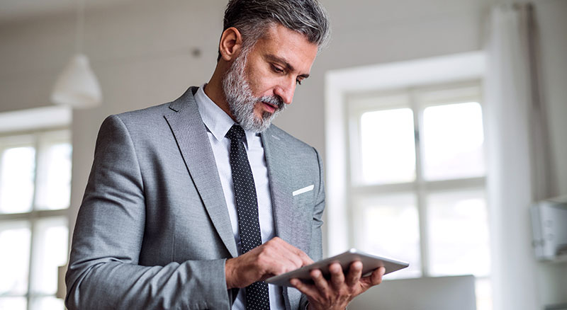 Everlytic | Blog | How to Reduce Your Email Bounce Rate & Boost Deliverability | Matured Man Wearing Suit | Using a Tablet