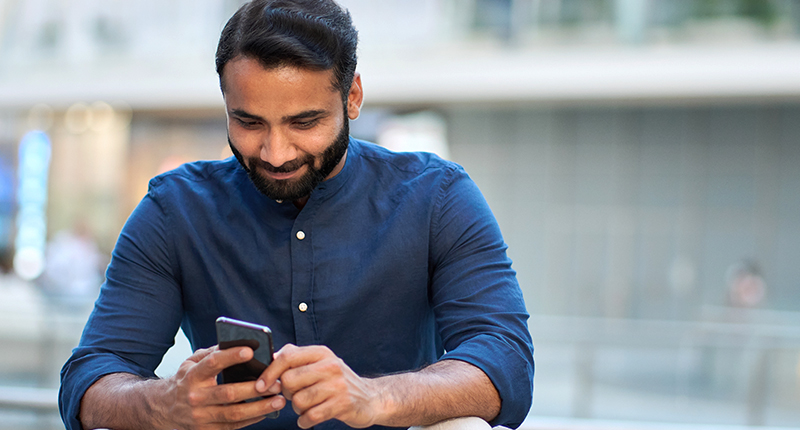 Boost Your Customer Support with the 5 Strengths of Transactional Email | Everlytic | Transactional Messaging | Happy Guy Reading Something Off a Cell Phone